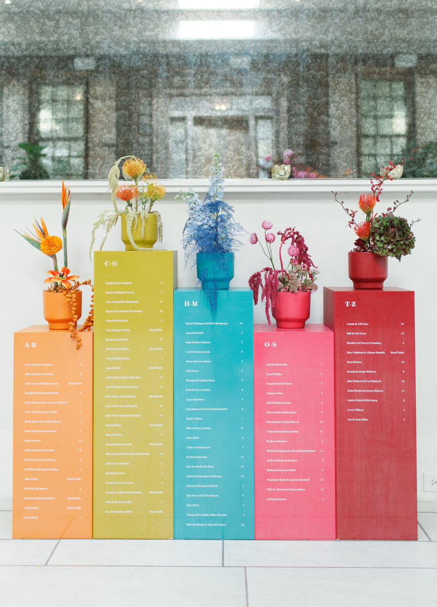 Museum-style pillars served double duty at an art-inspired wedding—displaying the seating chart but also holding floral arrangements that matched the color-block style.