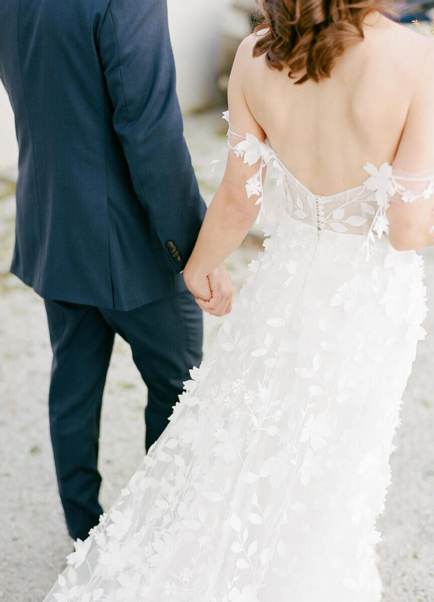 A groom and bride hold hands and walk towards the reception of their art-inspired wedding in Charleston.