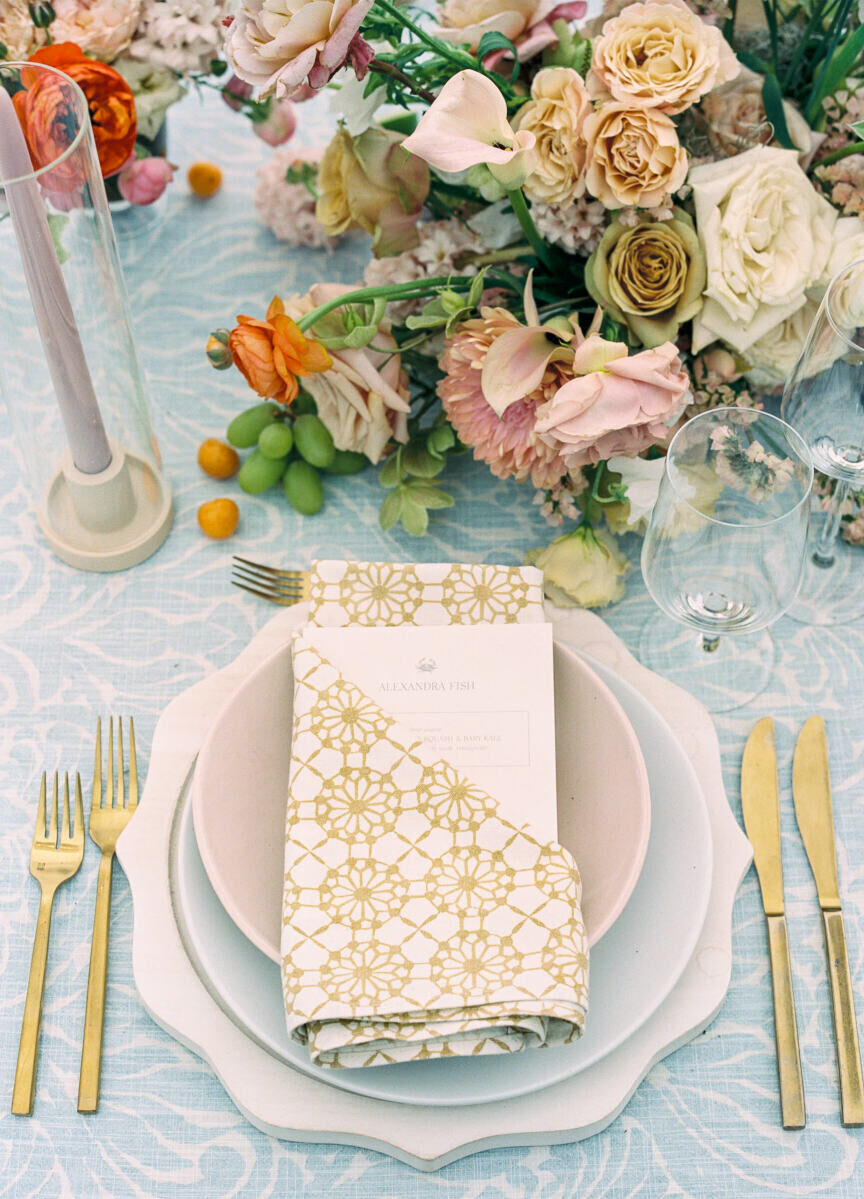 Matte taupe and pale blue plates sat atop fluted chargers flanked by modern gold flatware at an elegant spring wedding.