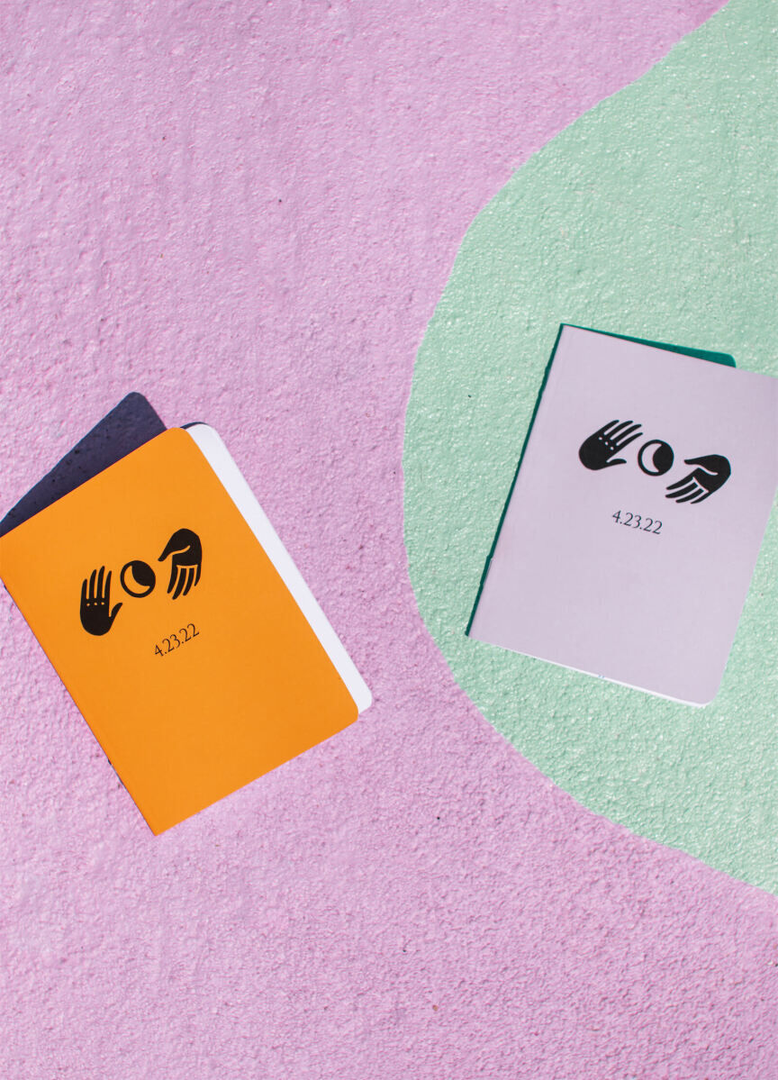 A motif of a moon and hands appeared on the stationery, signage, and other decor throughout this vibrant outdoor wedding. Here, a pair of vow books that the couple held during their California ceremony.