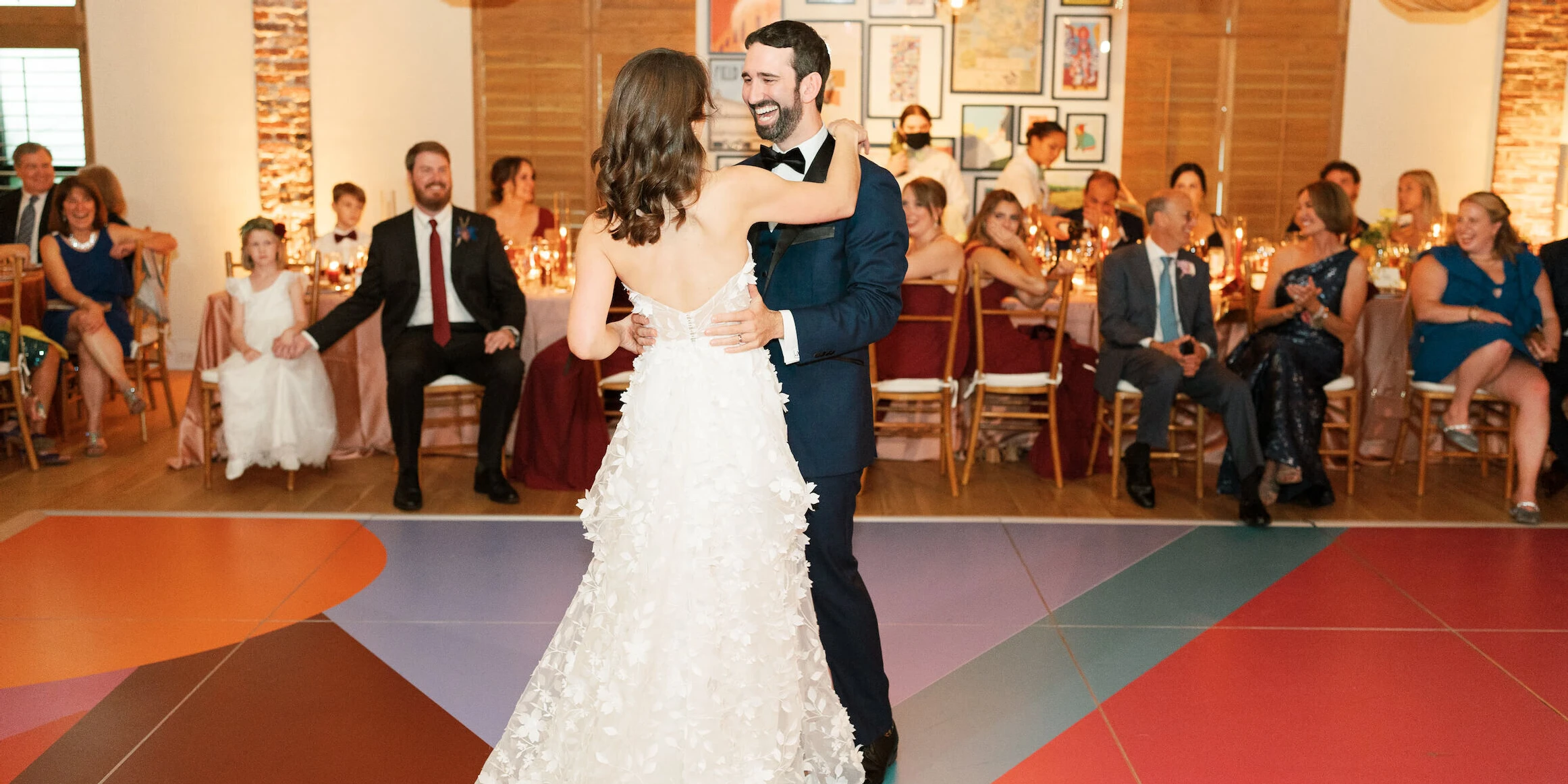 A bride and groom share their first dance on a colorful dance floor at their art-inspired wedding reception.